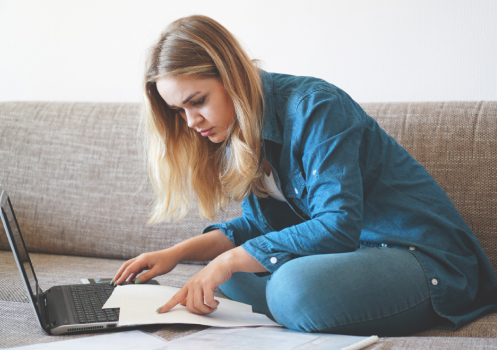 Woman reading documents while in front of laptop